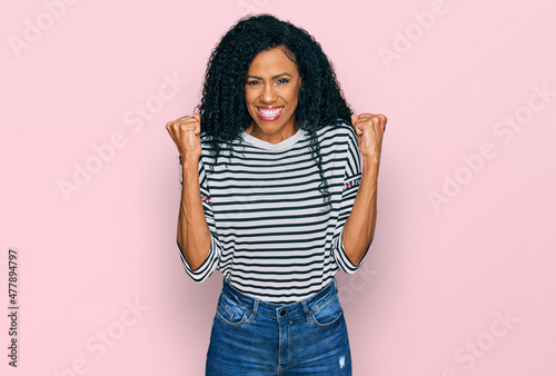 Middle age african american woman wearing casual clothes celebrating surprised and amazed for success with arms raised and open eyes. winner concept.