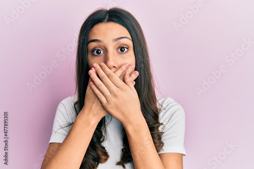 Young hispanic woman wearing casual white t shirt shocked covering mouth with hands for mistake. secret concept. © Krakenimages.com
