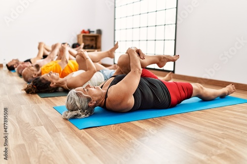 Group of middle age people stretching at sport center.