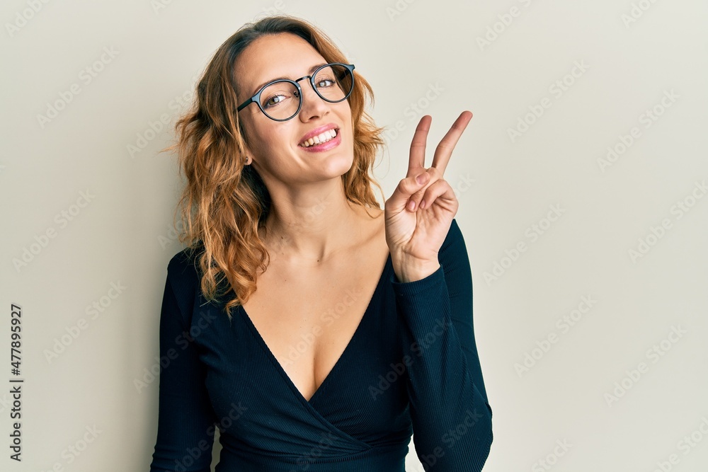 Young caucasian woman wearing business shirt and glasses showing and pointing up with fingers number two while smiling confident and happy. Young caucasian woman wearing business shirt and glasses showing and pointing up with fingers number two while smiling confident and happy.