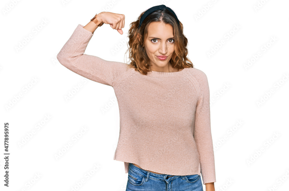 Obraz premium Beautiful young caucasian woman wearing casual sweater strong person showing arm muscle, confident and proud of power