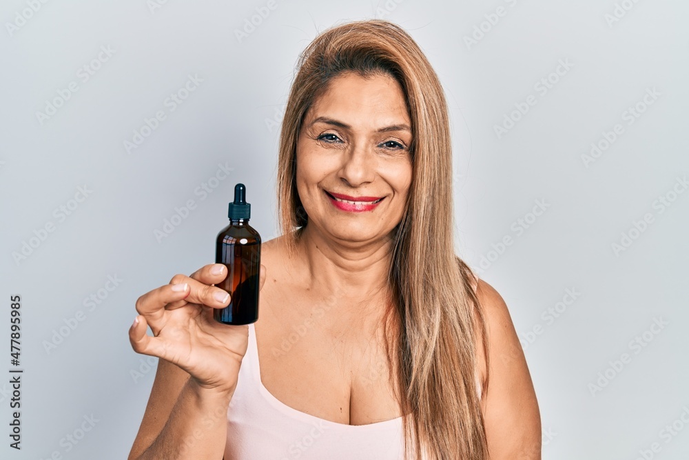 Middle age hispanic woman using night serum looking positive and happy standing and smiling with a confident smile showing teeth Middle age hispanic woman using night serum looking positive and happy standing and smiling with a confident smile showing teeth