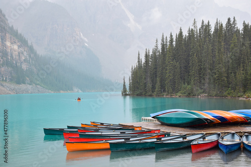 Turquoise blue lake with mountains and multiple colourful canoes