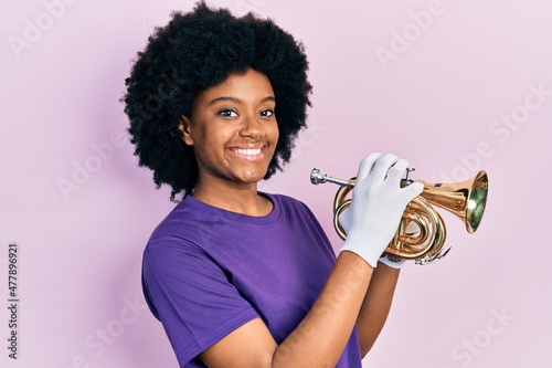 Canvas Print Young african american woman playing trumpet smiling with a happy and cool smile on face