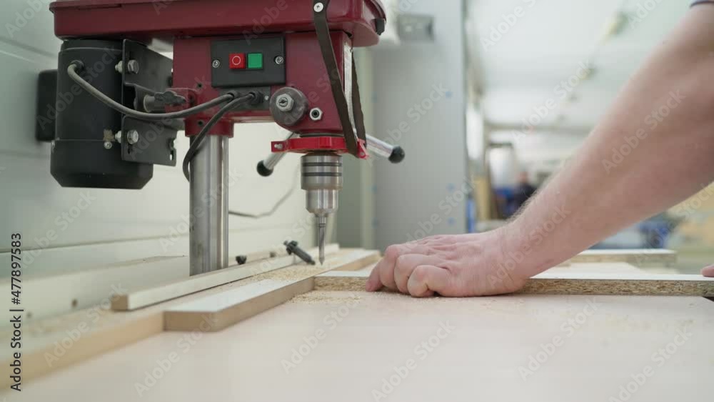 Close-up of a carpenter's hand drilling wood while working in carpentry. A furniture production worker works at a drilling table. Close-up of a carpenter's hand drilling wood while working in carpentry. A furniture production worker works at a drilling table.