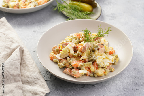 traditional east european dish for New Year's Eve - salad "Olivier" with potatoes, carrots, onion, peas, sausage, cucumbers, eggs and mayonnaise in a grey bowl