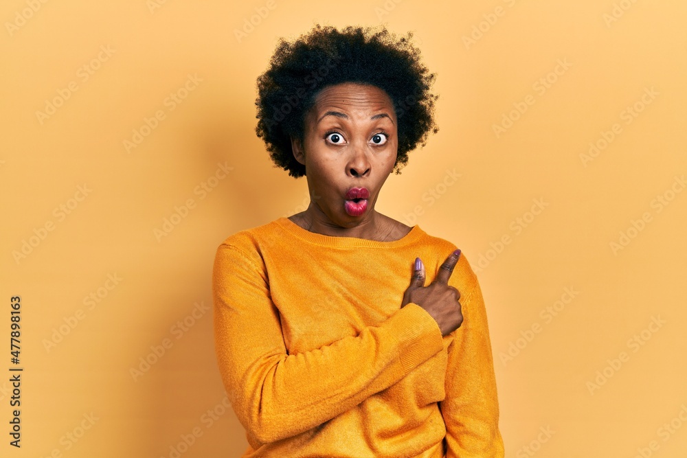 Young african american woman wearing casual clothes surprised pointing with finger to the side, open mouth amazed expression. Young african american woman wearing casual clothes surprised pointing with finger to the side, open mouth amazed expression.