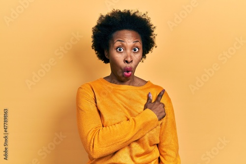 Young african american woman wearing casual clothes surprised pointing with finger to the side, open mouth amazed expression. © Krakenimages.com