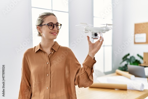 Young blonde woman smiling confident holding drone at architect studio