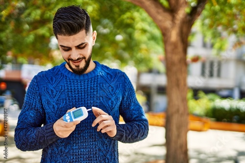 Obraz na płótnie Young arab man smiling confident holding glucometer at park