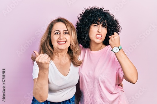 Middle east mother and daughter wearing casual clothes angry and mad raising fist frustrated and furious while shouting with anger. rage and aggressive concept.
