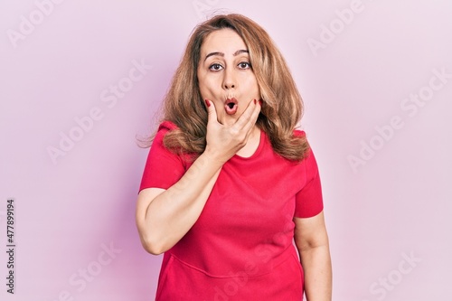 Middle age caucasian woman wearing casual clothes looking fascinated with disbelief, surprise and amazed expression with hands on chin