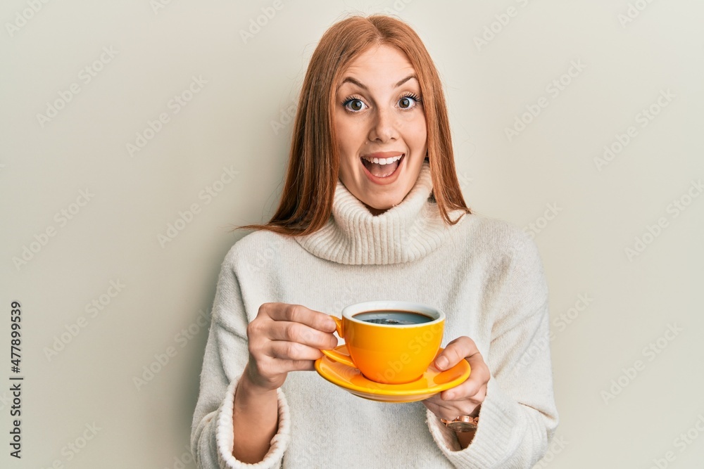 Young irish woman drinking a cup of coffee celebrating crazy and amazed for success with open eyes screaming excited. Young irish woman drinking a cup of coffee celebrating crazy and amazed for success with open eyes screaming excited.