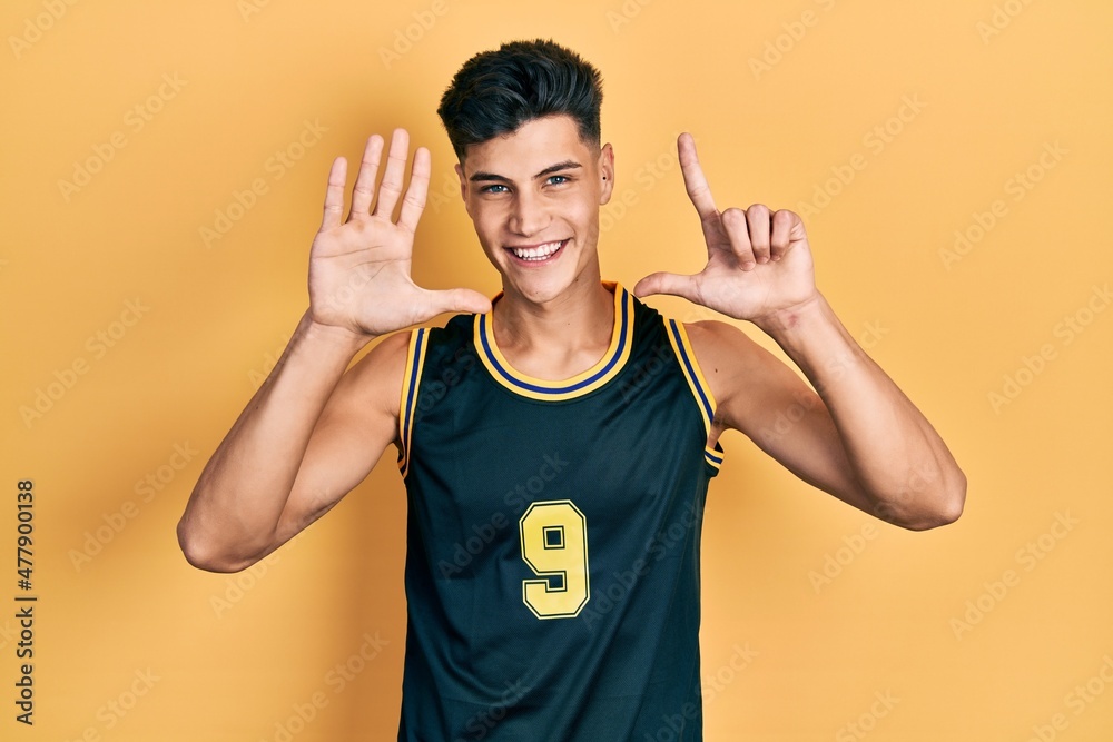 Young hispanic man wearing basketball uniform showing and pointing up with fingers number seven while smiling confident and happy. Young hispanic man wearing basketball uniform showing and pointing up with fingers number seven while smiling confident and happy.