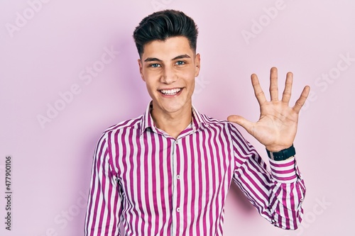 Young hispanic man wearing casual clothes showing and pointing up with fingers number five while smiling confident and happy.