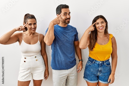 Group of young hispanic people standing over isolated background smiling pointing to head with one finger  great idea or thought  good memory