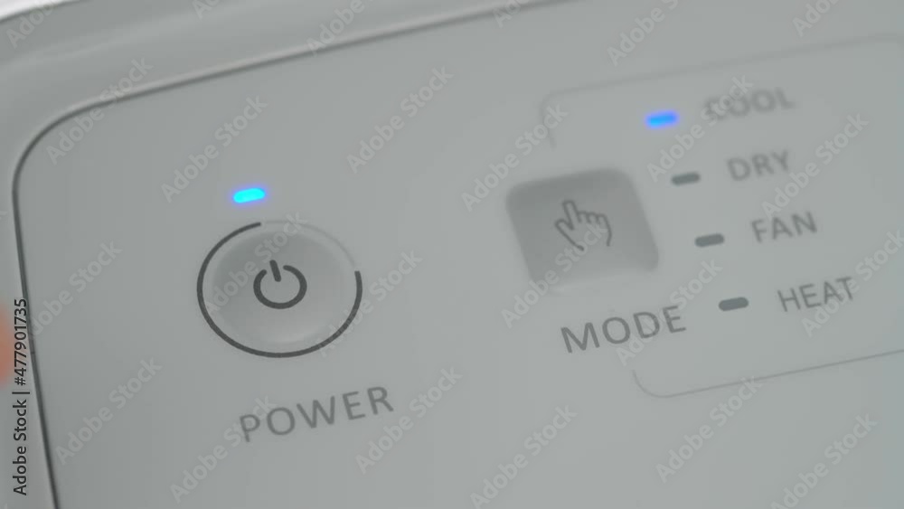 The person presses the start button on the mobile air conditioner to cool the room. Close-up. The person presses the start button on the mobile air conditioner to cool the room. Close-up.