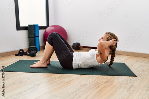 Young caucasian woman training abs exercise at sport center