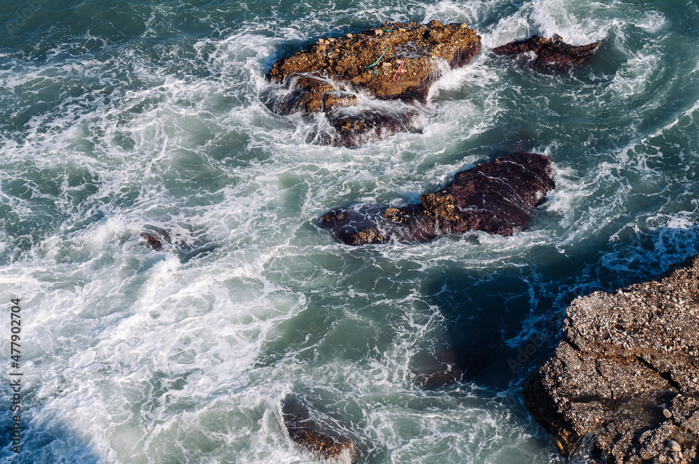 Obraz premium Aerial drone view of the ocean and waves crashing on rocks.