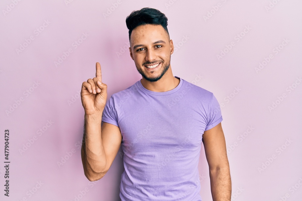 Young arab man wearing casual clothes pointing finger up with successful idea. exited and happy. number one. Young arab man wearing casual clothes pointing finger up with successful idea. exited and happy. number one.