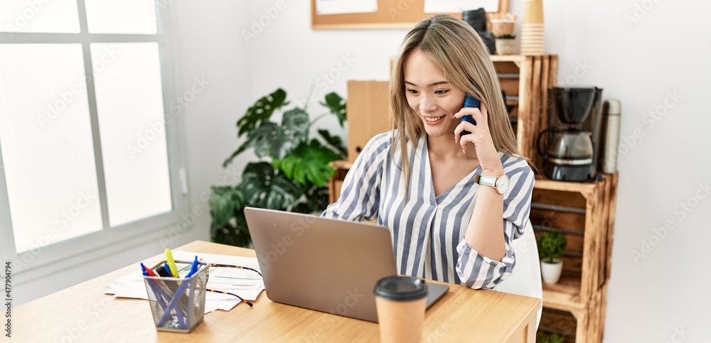 Young chinese woman talking on the smartphone working at office Young chinese woman talking on the smartphone working at office