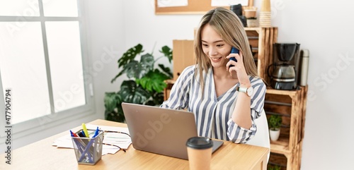 Young chinese woman talking on the smartphone working at office