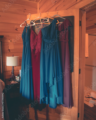 A photo of 4 dresses, alternating blue and red with a warm wood background. 