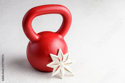 Kettlebell winter fitness, red kettlebell on a white background with silver sparkles and a white snowflake
