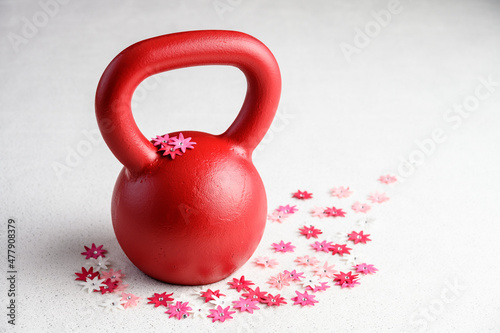Fototapeta Naklejka Na Ścianę i Meble -  Kettlebell spring fitness, red kettlebell on a white background with silver sparkles and red, pink, and white flowers

