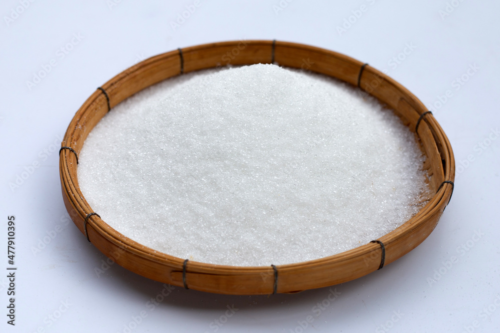 Granulated sugar in bamboo basket on white background.