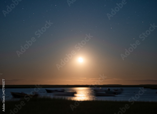 Boats Blurred by Motion of Ocean as the Moon Rises at Night