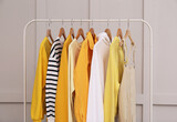 Rack with stylish women's clothes near light wall