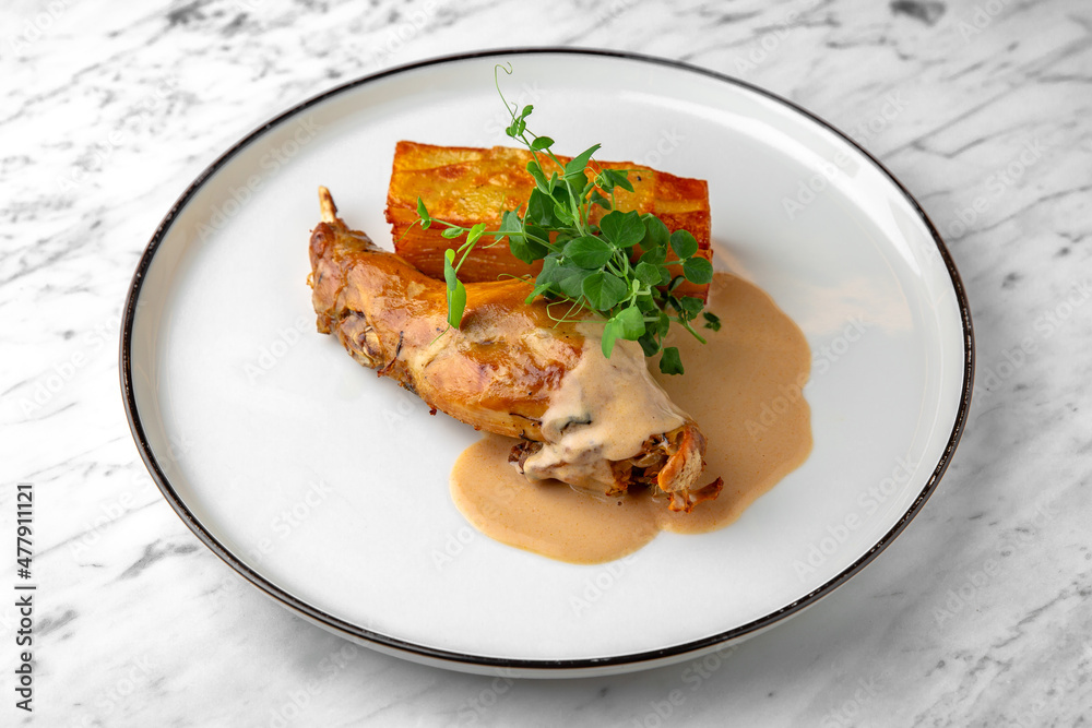 Baked rabbit leg with pumpkin pie in a festive plate on a marble background. Restaurant banquet menu. Baked rabbit leg with pumpkin pie in a festive plate on a marble background. Restaurant banquet menu.
