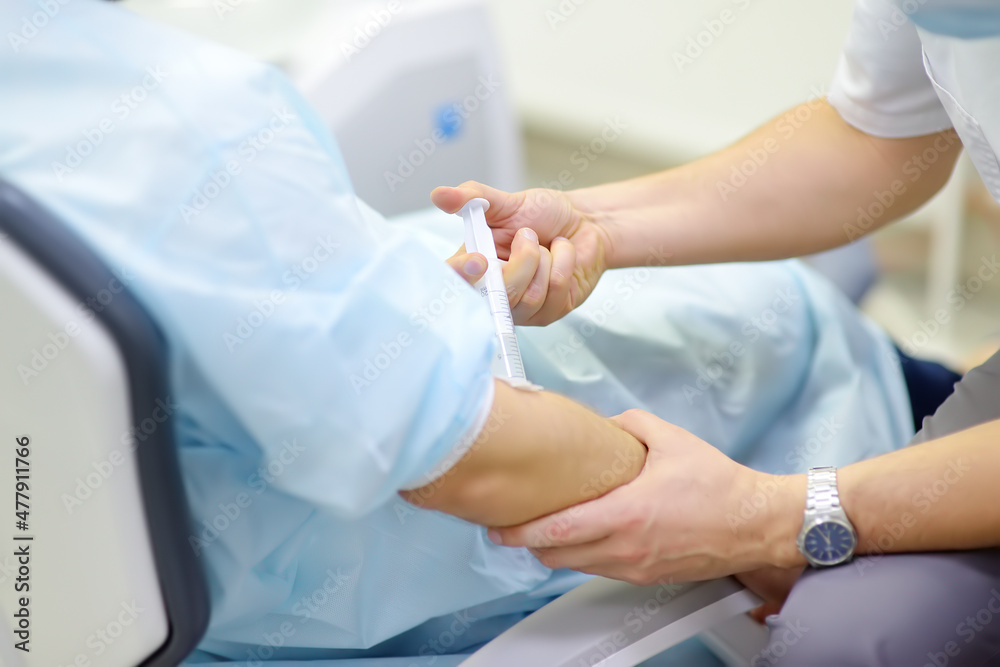 Anesthesiologist injects anesthesia into the patient's vein during dental surgery. Anesthetized patient in the operating room. Installation of dental implants in the clinic.