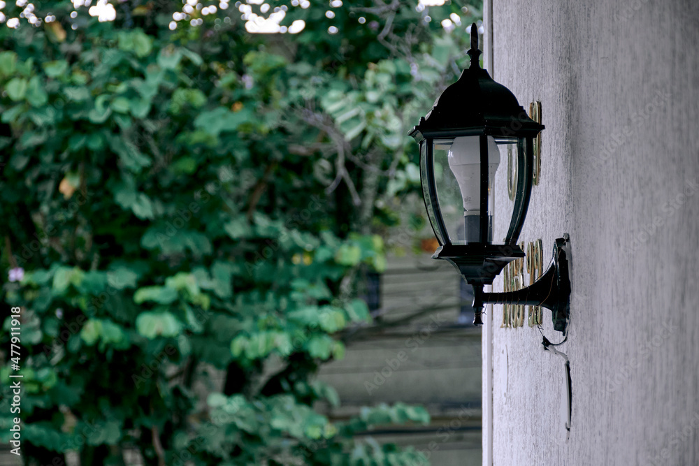Old lamp on white wall and green trees