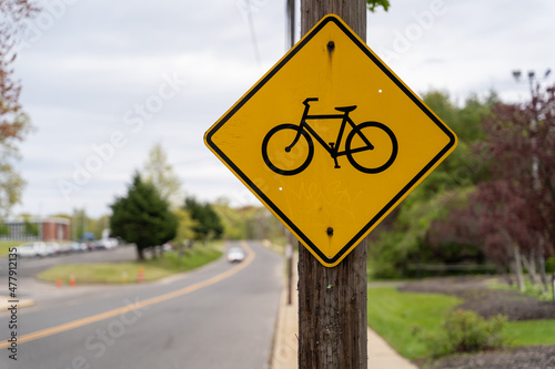 Bicycle lane warning sign posted on utility pole along suburban road warning car drivers to caution around bike riders