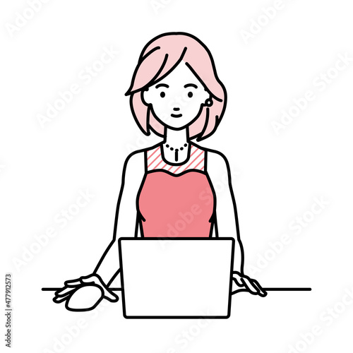 デスクで座ってPCを使っているドレスの女性