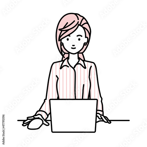 デスクで座ってPCを使っているブラウスの女性