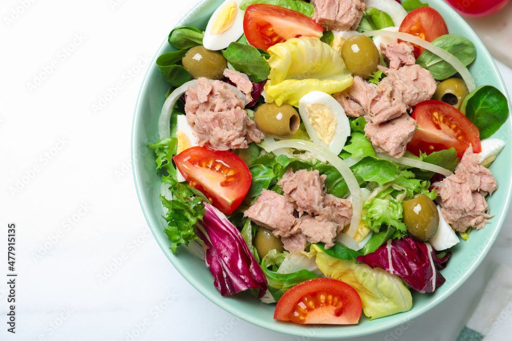 Bowl of delicious salad with canned tuna and vegetables on white table, top view