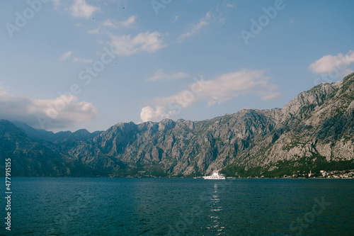 White yacht sails on the Bay of Kotor against the backdrop of a mountain range