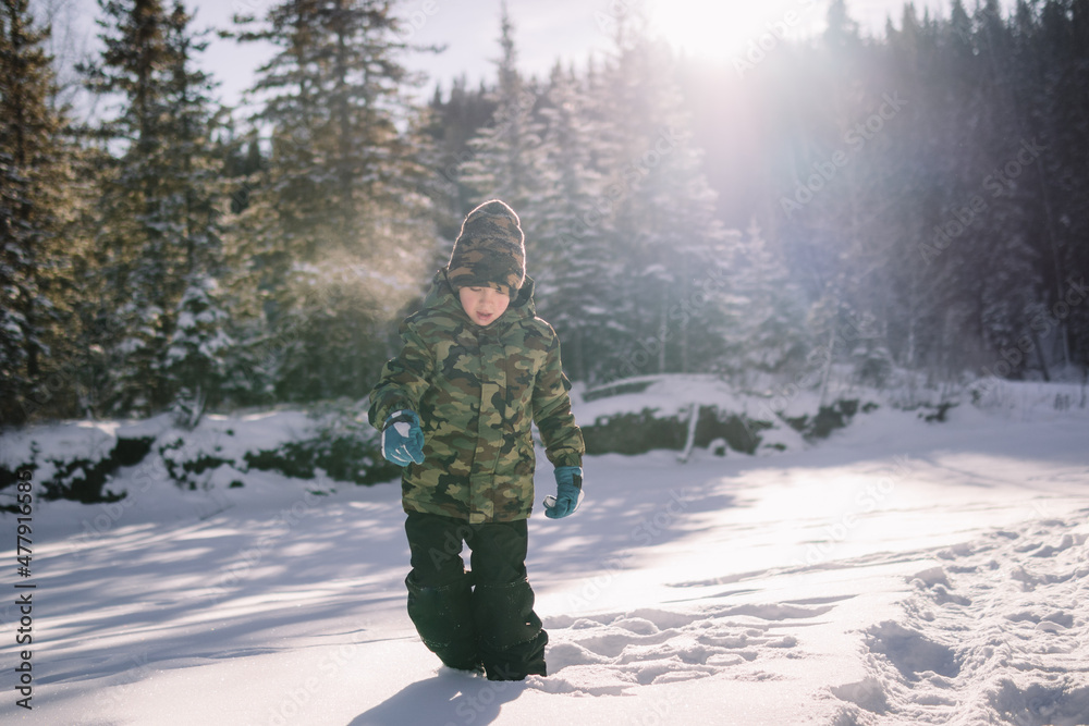 Young boy playing in the snow on a wintry day