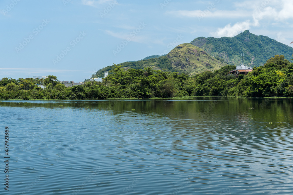 View of Lagoinha das Taxa in Parque Chico Mendes in Rio de Janeiro, Brazil. Some buildings, vegetation and hills in the background. Sunny day with blue sky View of Lagoinha das Taxa in Parque Chico Mendes in Rio de Janeiro, Brazil. Some buildings, vegetation and hills in the background. Sunny day with blue sky