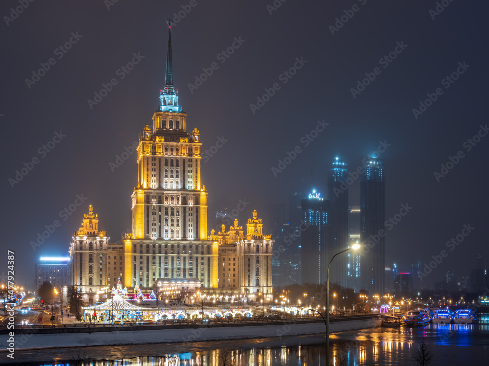 Illuminated high-rise stalinist building near river at winter night in Moscow, Russia. Historic name is Hotel Ukraine.