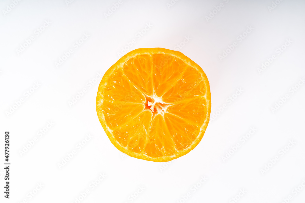 Fototapeta premium Half orange colored tangerine in the middle of a white background