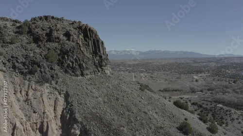 Drone flying past a rock formation revealing vast westlandscape with mountains photo