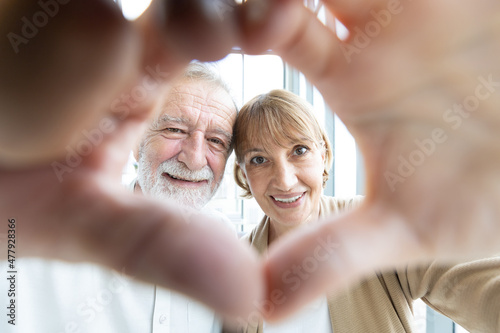 portrait senior couple smiling and making a heart shape with their hands