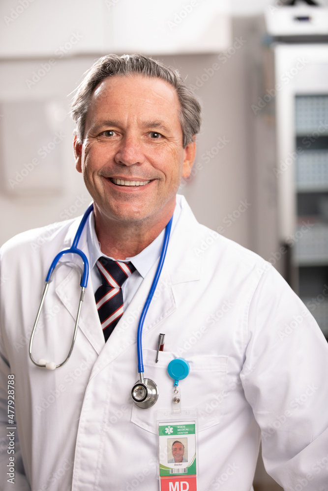 A Portrait of a White Male Medical Doctor with a Generic ID Badge wearing a Lab Coat and Stethoscope in a Hospital or Health Clinic. Mid Shot. A Portrait of a White Male Medical Doctor with a Generic ID Badge wearing a Lab Coat and Stethoscope in a Hospital or Health Clinic. Mid Shot.