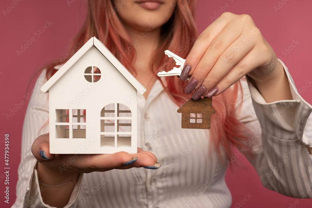 Beautiful female hands hold keys and a house on the background Beautiful female hands hold keys and a house on the background