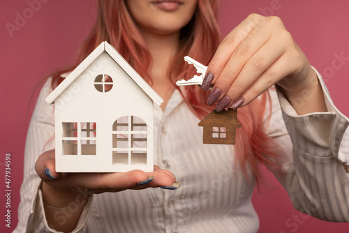 Beautiful female hands hold keys and a house on the background