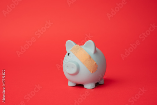 Broken piggy bank with beige adhesive on red background.